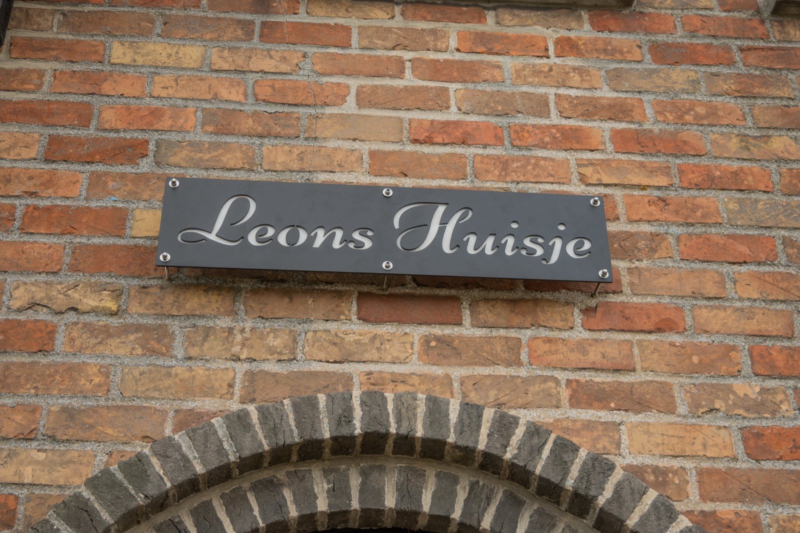 Naambord Leons Huisje boven de boogdeur in warme baksteen