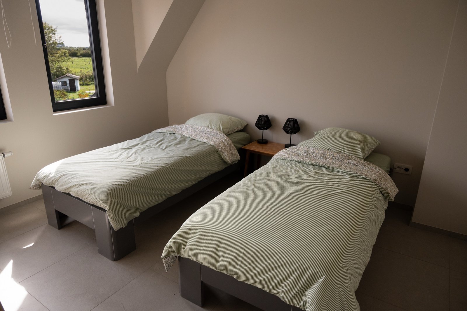 Twee opgemaakte eenpersoonsbedden in slaapkamer 1