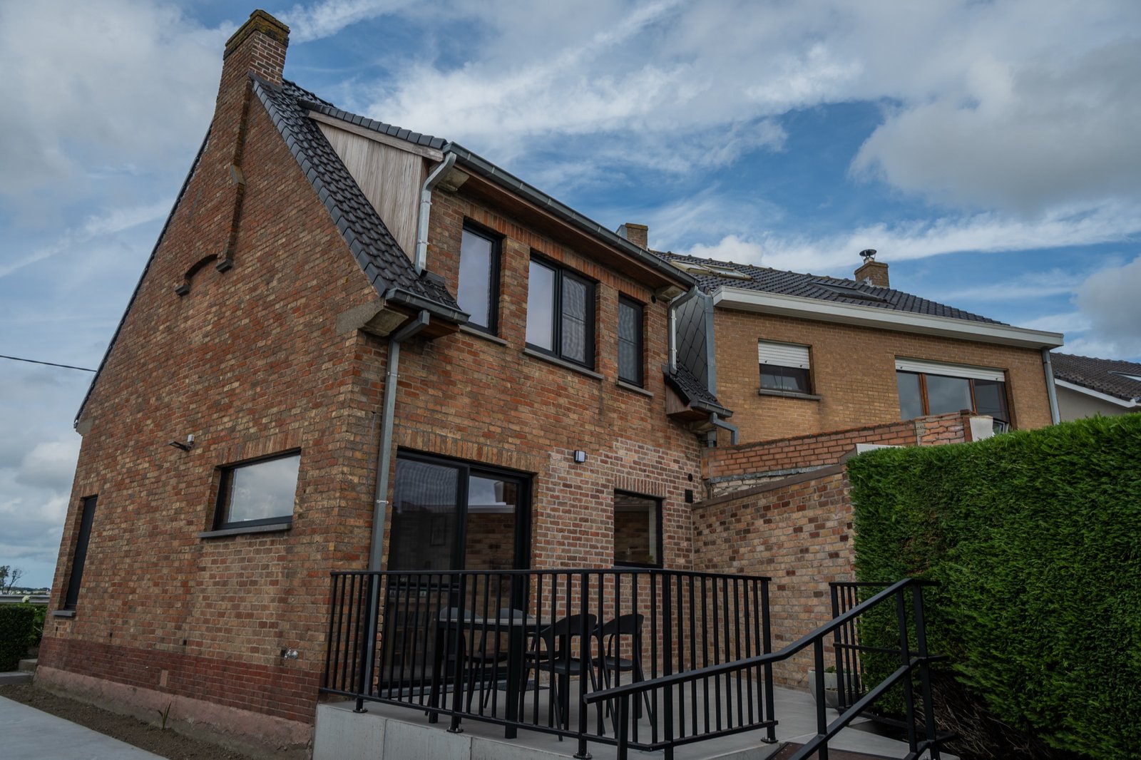 Achterkant van Leon's Huisje met terras en haag